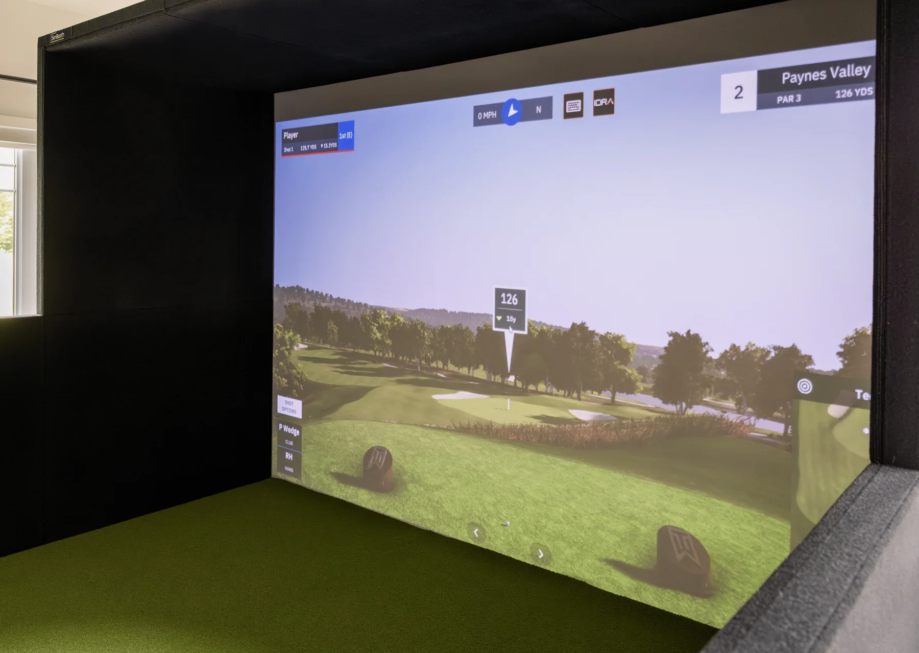Wide projection screen framed by a full golf simulator enclosure with protective side panels