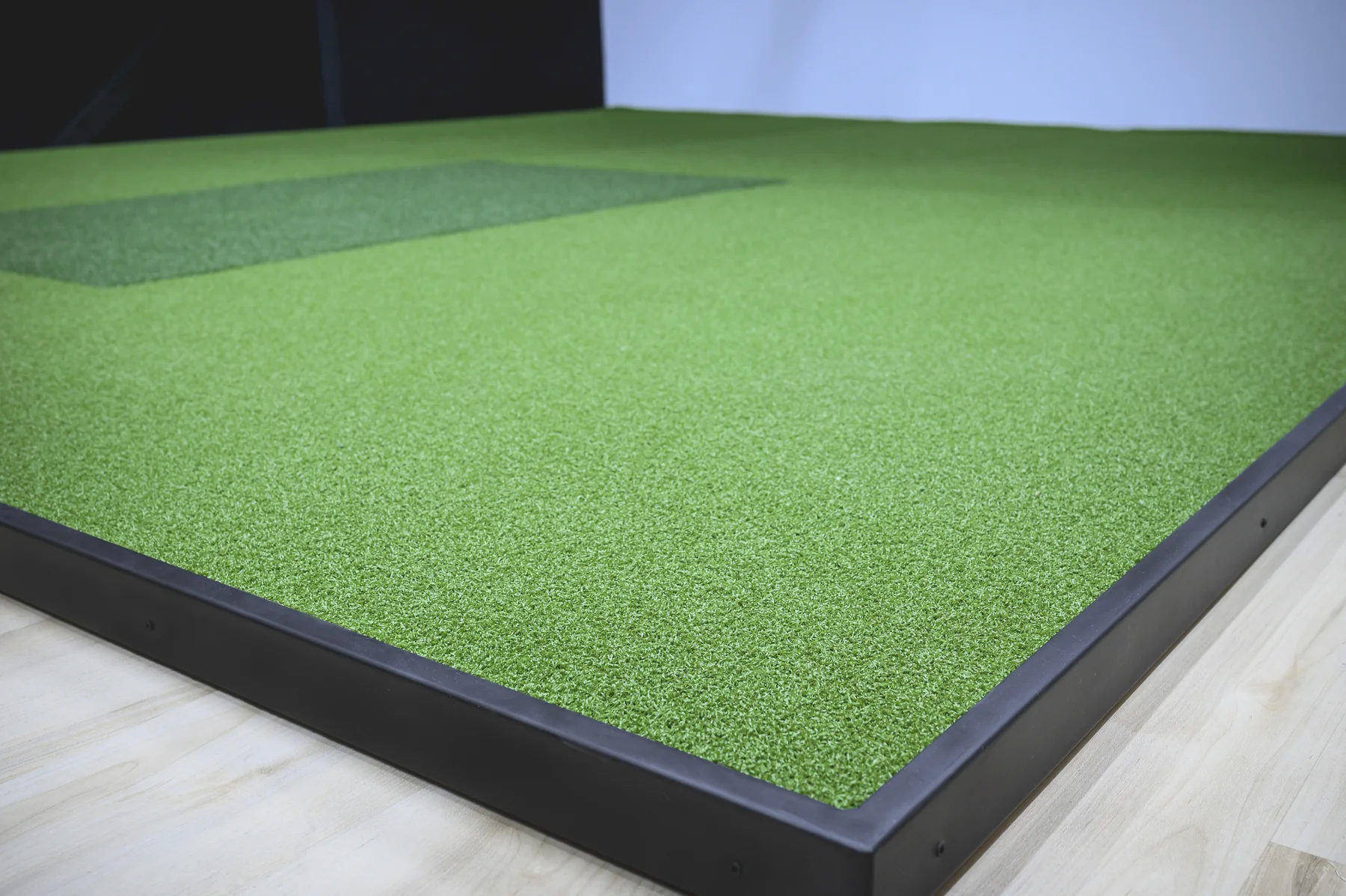 Full-surface golf simulator turf with a defined hitting area and finished edge